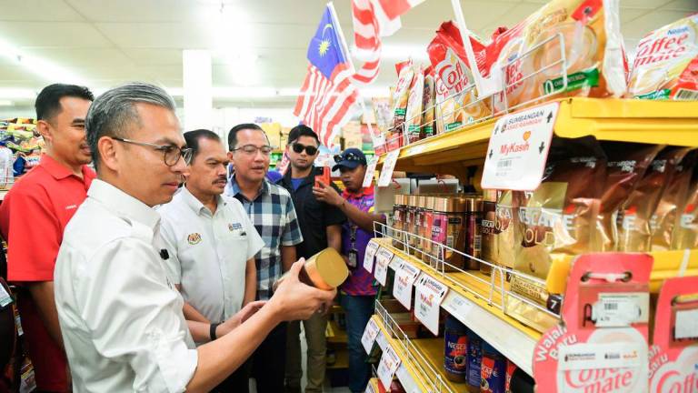 Menteri Komunikasi Datuk Fahmi Fadzil melihat harga barangan yang dijual pada harga Rahmah ketika meninjau penggunaan Sumbangan Asas Rahmah (SARA) di sebuah pasaraya di Merotai hari ini. Turut hadir Ketua Setiausaha Kementerian Komunikasi Datuk Seri Mohamad Fauzi Md Isa (dua, kiri). - BERNAMA