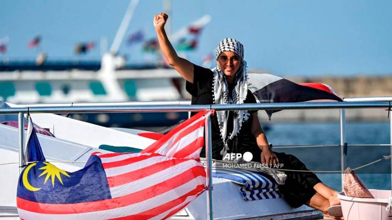 A woman gestures as she rides aboard a vessel with other activists and human rights defenders, departing from Tunisia's northern port of Bizerte, on September 14, 2025 to join the last boats taking part in the Global Sumud Flotilla, bound for the Gaza Strip to break Israel's blockade on the Palestinian territory. - AFP