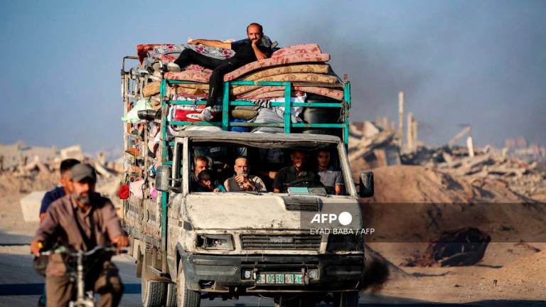 Palestinians fleeing south, ride a truck with their belongings, on the coastal road near the Nuseirat refugee camp in the central Gaza Strip, on August 5, 2025. - AFP