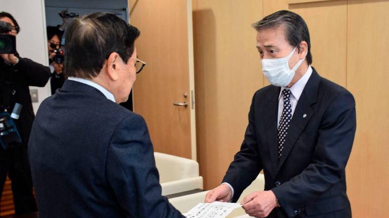 (FILES) This file photo taken on February 29, 2024 shows Mayor Hideo Kojima (R) handing over his resignation to chairman Akira Sakurai (L) in the town of Ginan, Gifu prefecture, after an official investigation accused Kojima of allegations of sexual harassment incidents.- Japan OUT (Photo by JIJI PRESS / AFP)
