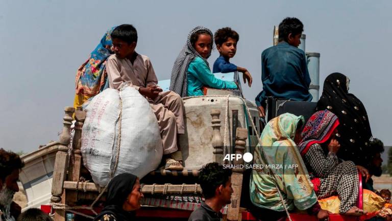 Penduduk kampung yang terjejas akibat banjir membawa barang-barang mereka menaiki traktor dan tiba berhampiran lebuh raya yang ditutup kerana rosak akibat air banjir di Jalalpur Pirwala, dalam daerah Multan di wilayah Punjab, pada 17 September 2025, selepas Sungai Chenab melimpah berikutan hujan monsun lebat. - AFP