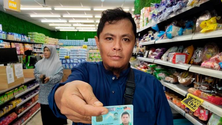 Penerima Sumbangan Asas Rahmah (SARA), Mohd Naim Mohd Zubir, 40, membeli barangan keperluan menggunakan sistem Mykad yang menurutnya ringkas dan tidak timbul karenah ketika pembayaran dan penerimaan baki di sebuah pasaraya hari ini - BERNAMA