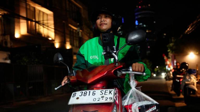 Pratiwi Ariyanti, 38, an Indonesian ride-hailing driver, rides her motorbike after picking up food ordered and donated by a customer from overseas through an app, in solidarity following the death of a ride-hailing driver and another injured in the widespread protests in Indonesia against government policies, in Jakarta, Indonesia, September 3, 2025. - REUTERSPIX