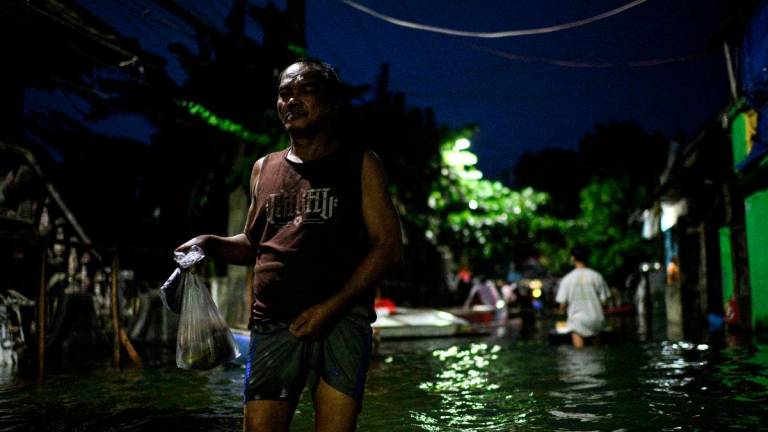 Seorang lelaki meredah jalan yang dibanjiri air selepas hujan lebat yang dipergiat oleh Ribut Tropika Kuat Bualoi, di Dela Paz, Binan, wilayah Laguna, Filipina, pada 26 September 2025. - Reuters
