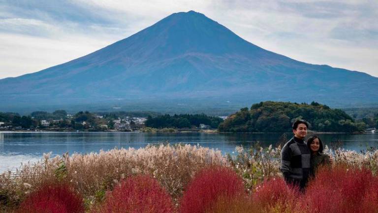 People take photographs before Mount Fuji, the highest mountain in Japan at 3,776 metres (12,460 feet), in Fujikawaguchiko, Yamanashi prefecture - AFPpix