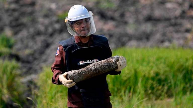 A deminer from the Cambodian Mine Action Centre carrying an unexploded ordnance in Svay Rieng province - AFPpix