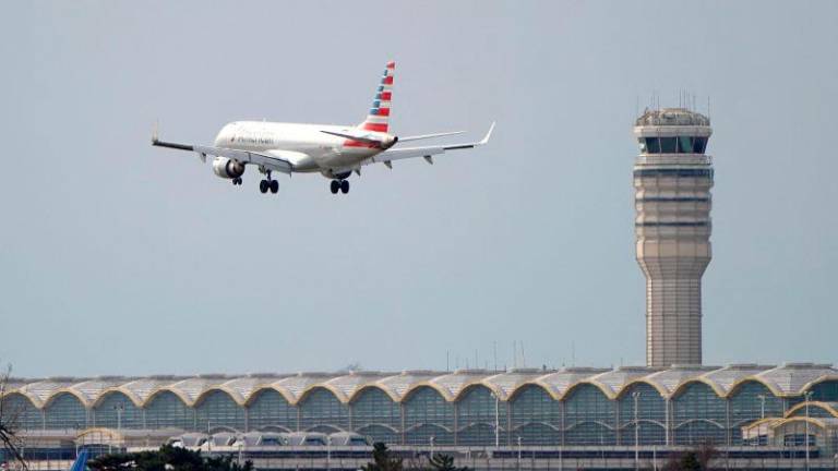 FILEpix: An American Airlines Embraer ERJ-190AR airplane flies past the tower where air traffic controllers work despite not receiving their paychecks, on the 22nd day of a partial government shutdown at Reagan National Airport in Washington, U.S., January 12, 2019. REUTERS