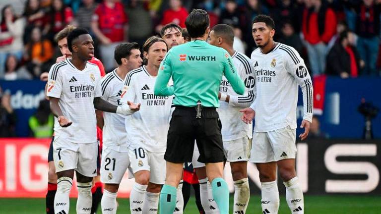 Real Madrid's players remonstrate with Spanish referee Munuera Montero about the red card presented to Real Madrid's English midfielder #05 Jude Bellingham (R) during the Spanish league football match between CA Osasuna and Real Madrid CF at El Sadar Stadium in Pamplona on February 15, 2025. - AFPPIX