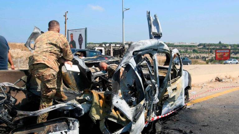 Lebanese army soldiers check the wreckage of a vehicle that was reportedly targeted by an Israeli strike, on the highway near the village of Ansarieyh, south of the coastal city of Sidon on August 8, 2025. Photo by Mahmoud ZAYYAT / AFP