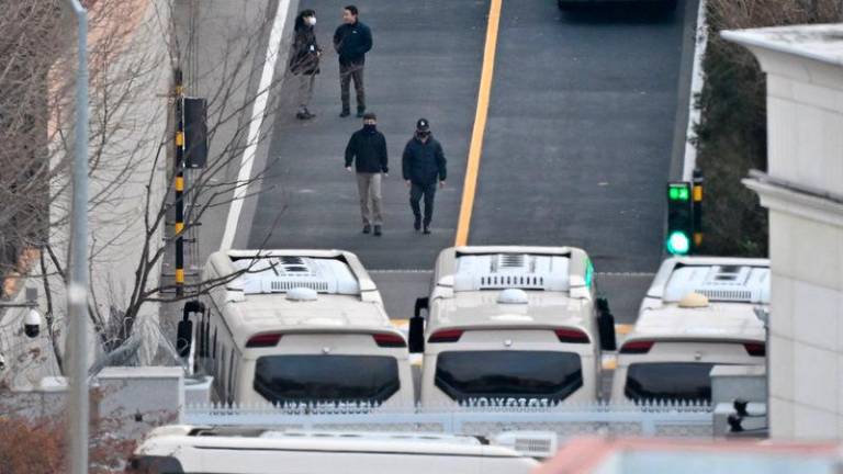 Security personnel walk on a road lined up with buses blocking the entrance gate to protect impeached South Korean president Yoon Suk Yeol - AFPpix