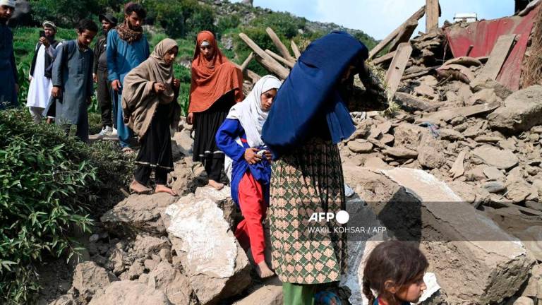 Afghan men and women walk past a damaged house following earthquakes in the Mazar Dara village of Nurgal, a district of the Kunar Province, in Eastern Afghanistan, on September 1, 2025. (Photo by Wakil Kohsar / AFP)