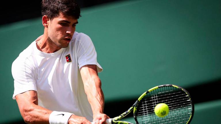 Spain's Carlos Alcaraz plays a backhand return to Italy's Fabio Fognini during their men's singles first round tennis match on the first day of the 2025 Wimbledon Championships at The All England Lawn Tennis and Croquet Club in Wimbledon, southwest London, on June 30, 2025. - AFPPIX