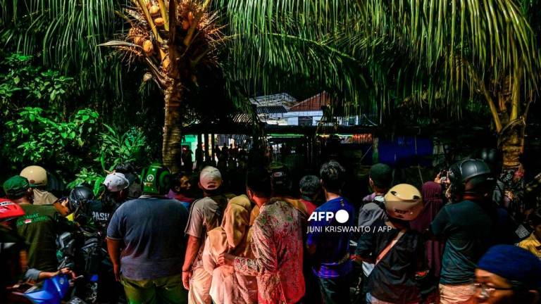 People gather to watch as a rescue operation is underway at the site of a collapsed building in a cordoned-off area at the Al Khoziny Islamic boarding school in Sidoarjo, East Java province, on October 2, 2025, after a multi-storey building at the school collapsed. - AFP