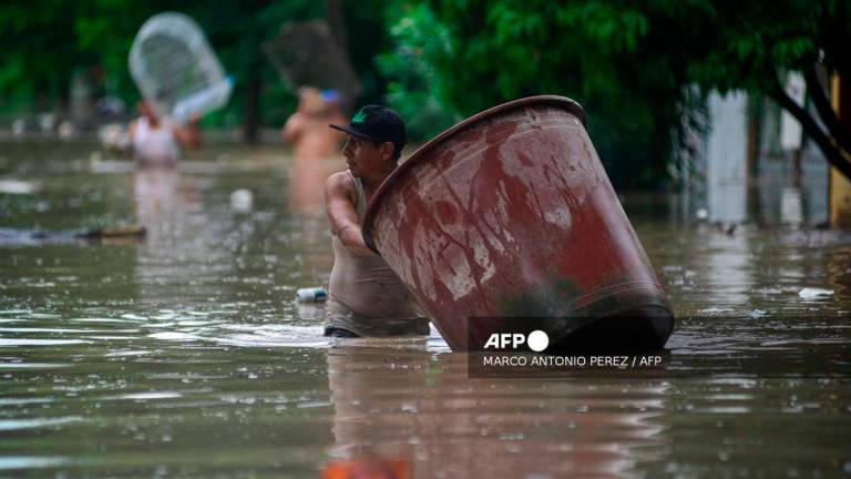 A man wades through a flooded street after heavy rains in Poza Rica, Veracruz state, Mexico on October 10, 2025. - AFP