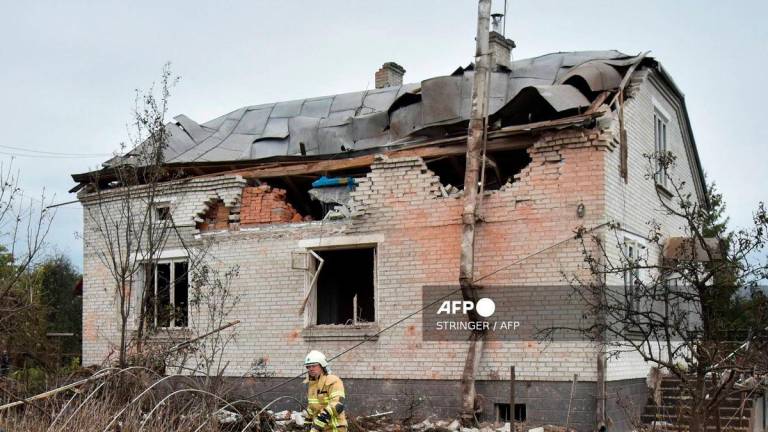 A Ukrainian rescuer walks in the courtyard of a destroyed house following an air attack in Lapaivka, Lviv region on October 5, 2025, amid the Russian invasion of Ukraine. (Photo by STRINGER / AFP)