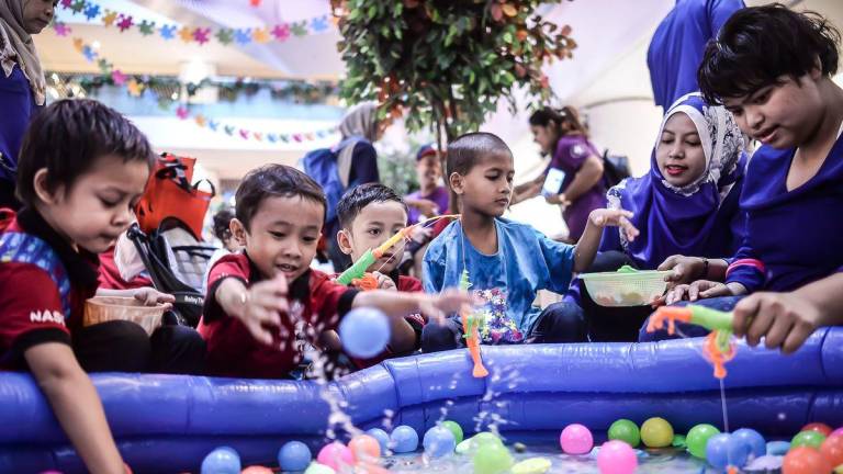 Kids from The National Autism Society of Malaysia (NASOM) playing while looking by parent during World Austism Day at Sunway Putra Mall. - Adib Rawi Yahya / theSun