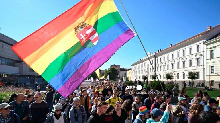 A participant holds a rainbow flag with the Hungarian crest during a pride march in Pecs, south-western Hungary, on October 4, 2025. - AFP
