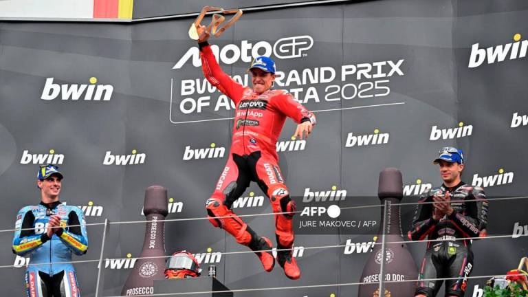 Winner Ducati Lenovo team's Spanish rider Marc Marquez (C) jumps on the podium as he celebrates next to second placed BK8 Gresini Racing MotoGP team's Spanish rider Fermin Aldeguer (L) and third placed Aprilia Racing team's Italian rider Marco Bezzecchi after the Austrian MotoGP Grand Prix at the Red Bull Ring race track in Spielberg, Austria, on August 17, 2025. - AFP