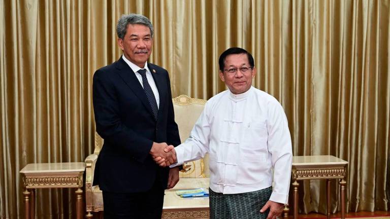This handout photo taken and released on October 9, 2025 by the Myanmar Military Information Team shows Myanmar’s military chief Min Aung Hlaing (R) shaking hands with Malaysia’s Foreign Minister Mohamad Hasan (L) during a meeting in Naypyidaw. -AFP PHOTO / MYANMAR MILITARY INFORMATION TEAM