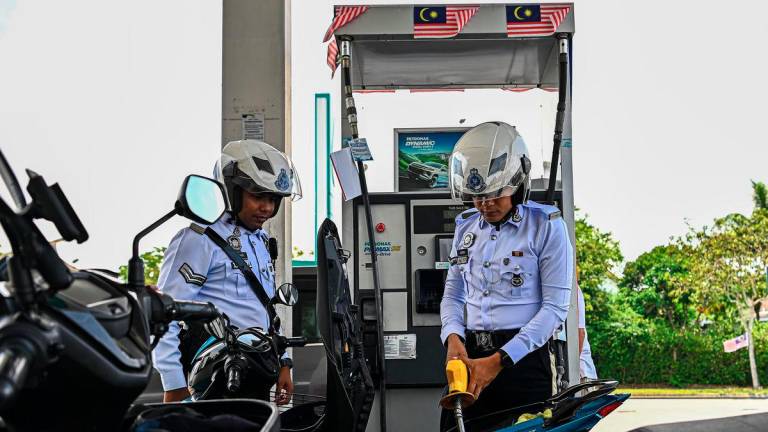 Traffic photographer from the Seremban District Police Headquarters (IPD), Azrin Abd Aziz (right), filled up with RON95 petrol at the Petronas S2 City Park station for RM1.99 per litre, compared to the market price of RM2.05 per litre, under the BUDI MADANI RON95 (BUDI95) initiative, which began today. – BERNAMA