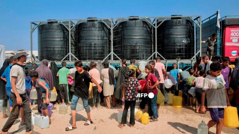 Displaced Palestinians attempt to fill water tanks in the Mawasi area of Khan Yunis, on August 14, 2025, as international organisations have been working to provide people with clean water amid the worsening crisis and the spread of diseases due to poor sanitation in the Gaza Strip. - AFP