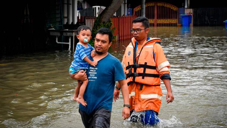 Pasukan keselamatan membantu mengeluarkan mangsa ke kawasan selamat selepas kediaman mereka dinaiki air ekoran hujan lebat berterusan selama tiga jam ketika tinjauan fotoBernama di Taman Bukit Kemuning, Seksyen 32 pagi ini -BERNAMA
