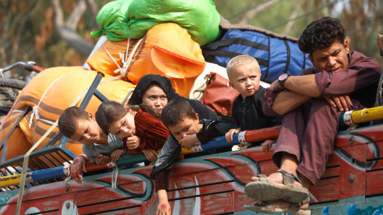 Afghan refugee children sit on a truck loaded with belongings as they along with their families prepare to return home, after Pakistan gives the last warning to undocumented immigrants to leave, outside the United Nations High Commissioner for Refugees (UNHCR) repatriation centres in Azakhel town in Nowshera, Pakistan October 30, 2023. - REUTERS