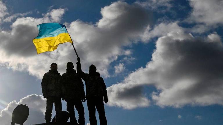 Ukrainian personnel hold a Ukrainian flag as they stand on a Challenger 2 tank during training at Bovington Camp, near Wool in southwestern Britain, February 22, 2023. REUTERS/Toby Melville/File Photo