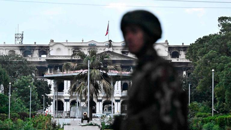 Army personnel stands guard near Singha Durbar, the main administrative building for the Nepal government, after it was set ablaze by protesters, in Kathmandu on September 12, 2025. The army has imposed a curfew in the Himalayan nation of 30 million people, with soldiers patrolling the largely quiet streets after the worst violence in two decades. (Photo by Pedro Pardo / AFP)
