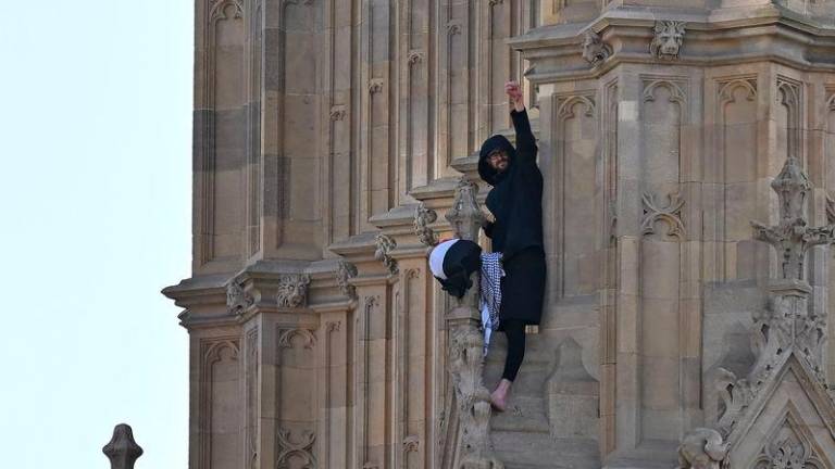 A protester holding a Palestinian flag gestures from the side of the Elizabeth Tower, commonly known by the name of the clock’s bell “Big Ben”. AFPpix