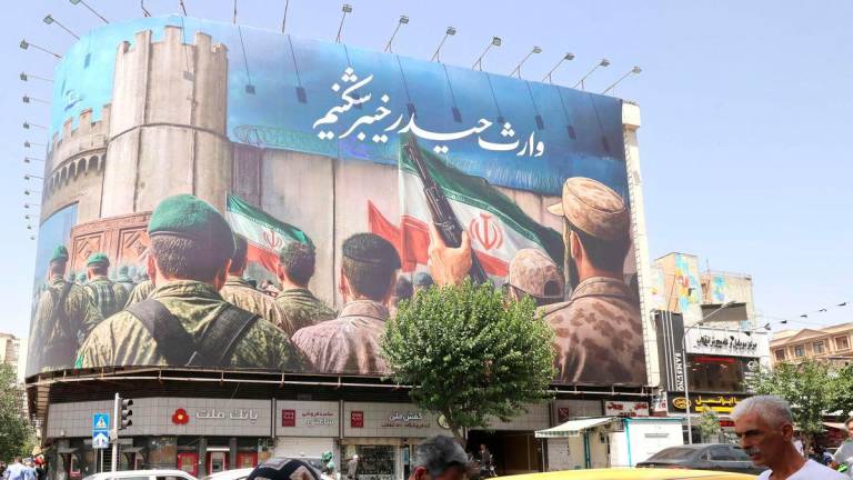 People walk past a huge banner on Enghelab (Revolution) Square, in Tehran on June 24, 2025. (Photo by ATTA KENARE / AFP)