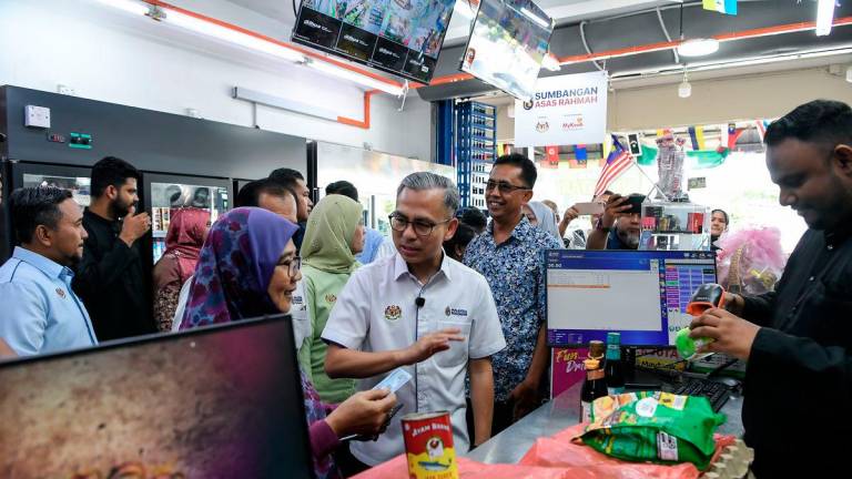 Communications Minister Datuk Fahmi Fadzil mingled with some recipients during an inspection of the Sumbangan Asas Rahmah (SARA) initiative in Kubang Semang here today. – BERNAMA