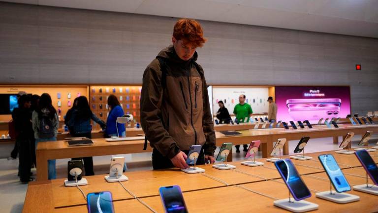 FILE PHOTO: A person looks at iPhones in the Apple Fifth Avenue store in New York City, U.S., May 23, 2025 - REUTERS