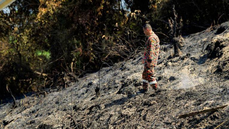 Anggota Bomba dan Penyelamat Zon 2 Negeri Perak melakukan pemantauan kawasan kebakaran hutan belukar yang terjejas seluas 23.47 hektar di Kampung Tersusun Tebuk Panchor, Gunung Semanggol hari ini. - fotoBERNAMA
