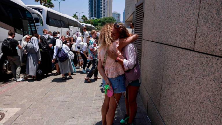 Women hug goodbye before the departure of a bus slated to evacuate foreign passport holders, mainly European and Polish, out of Israel, at a meeting point in Tel Aviv on June 17, 2025. (Photo by Menahem KAHANA / AFP)