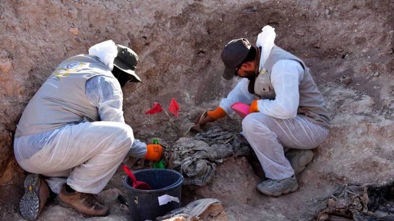 Workers dig out human remains at the Khasfa site near the northern Iraqi city of Mosul, where authorities have begun excavating a mass grave believed to contain thousands of victims of the Islamic State (IS) on August 17, 2025. Official estimates put the number of bodies buried at the site at at least 4,000, with the possibility of thousands more. (Photo by Zaid AL-OBEIDI / AFP)