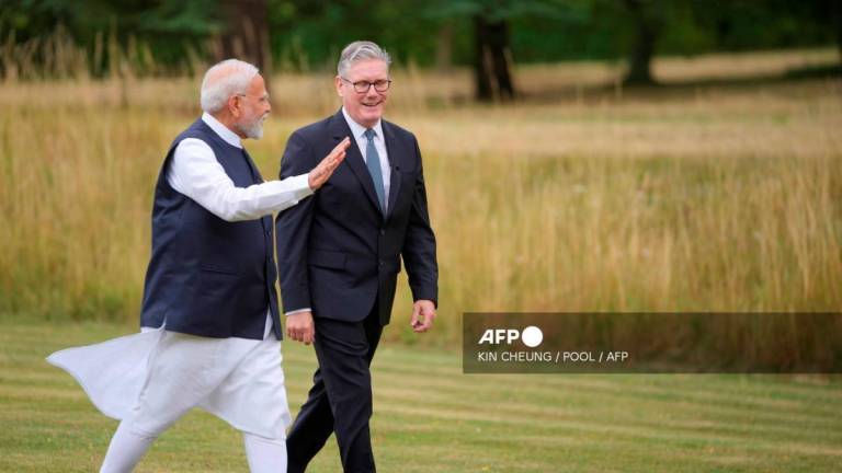 Britain's Prime Minister Keir Starmer (R) and India's Prime Minister Narendra Modi (L) speak as they walk in the gardens of Chequers, in Aylesbury, England, on July 24, 2025. - POOL via AFP