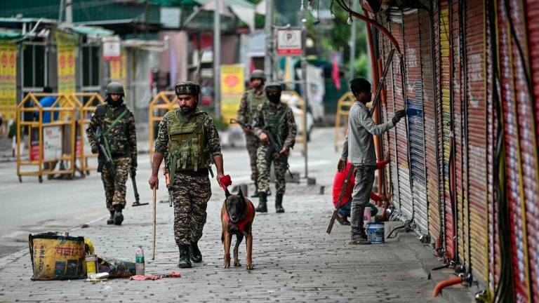 Indian paramilitary soldiers with a sniffer dog patrol at a marketplace in Srinagar on May 10, 2025. - AFPPIX