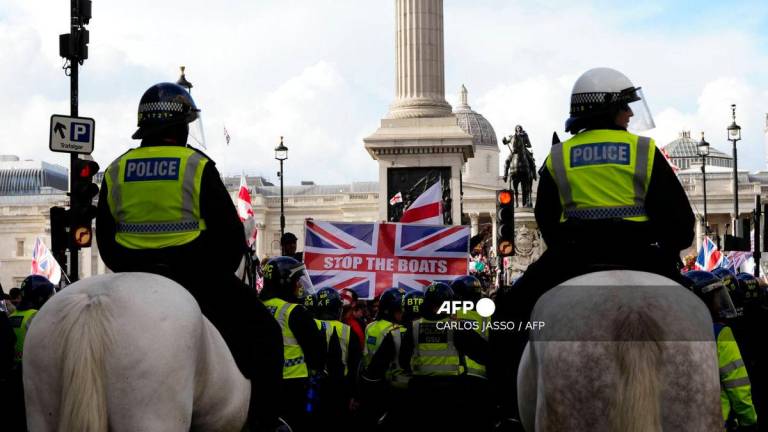 Mounted police officers look on as a Union Jack flag is displayed by supporters of British far-right activist Tommy Robinson whose real name is Stephen Yaxley-Lennon, during a ‘Free speech’ march, in central London on September 13, 2025. (Photo by CARLOS JASSO / AFP)