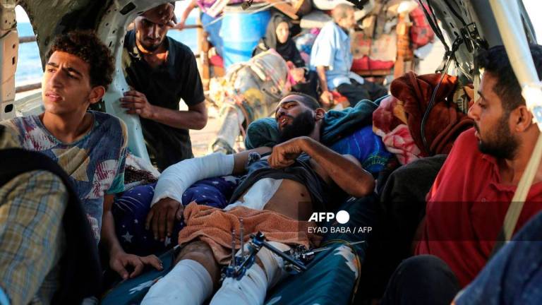 A wounded man lies in a vehicles as displaced Palestinians move with their belongings southwards on a road in the Nuseirat refugee camp area in the central Gaza Strip on September 23, 2025, as Israel presses its ground offensive to capture Gaza City amidst the war against Hamas. - AFP