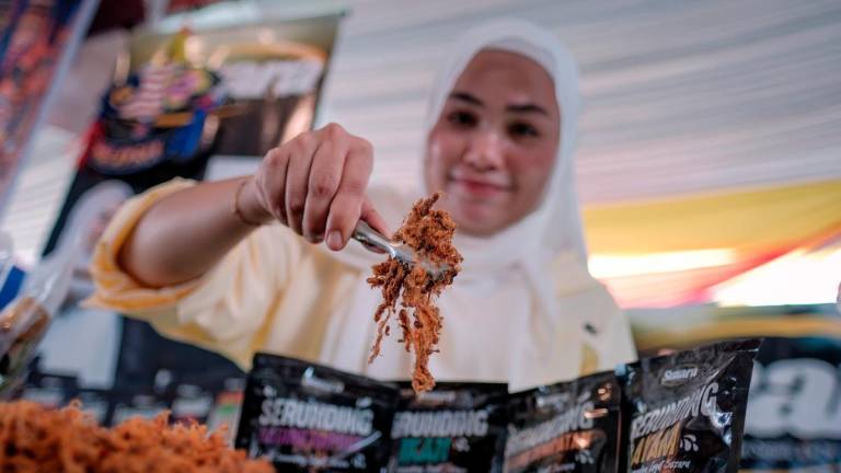 Usahawan dodol Nur Atikah Syazwani Hassan, 30, menunjukkan produk serunding yang turut dijual selain dodol telur dan dodol gelembung buaya pada Karnival Kita MADANI yang diadakan bersempena dengan Majlis Peluncuran Bulan Kebangsaan dan Kibar Jalur Gemilang 2025 di Dataran Tanjung Emas di sini hari ini - BERNAMA