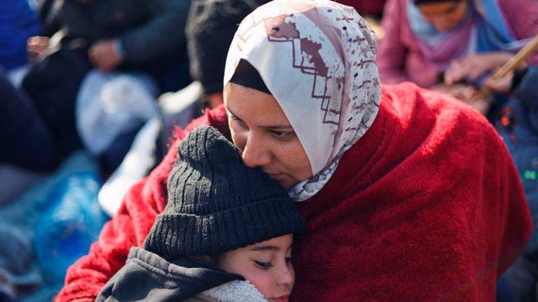 A woman embraces a child as Palestinians wait to be allowed to return to their homes in northern Gaza - REUTERSpix