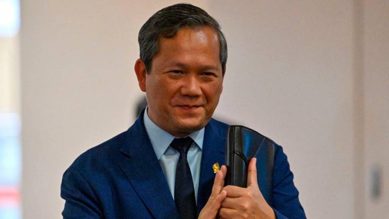 Cambodia’s Prime Minister Hun Manet greets people as he arrives to attend a meeting at the National Assembly building in Phnom Penh on August 25, 2025, where Cambodian lawmakers are expected to pass laws allowing for citizenship to be stripped. (Photo by TANG CHHIN Sothy / AFP)