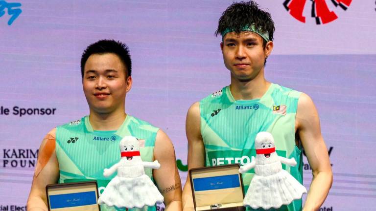 Aaron Chia and Soh Wooi Yik of Malaysia pose after their victory against Kim Won-ho and Seo Seung-jae of South Korea in their men’s doubles final match at the Singapore Open badminton tournament in Singapore on June 1, 2025. AFPpix