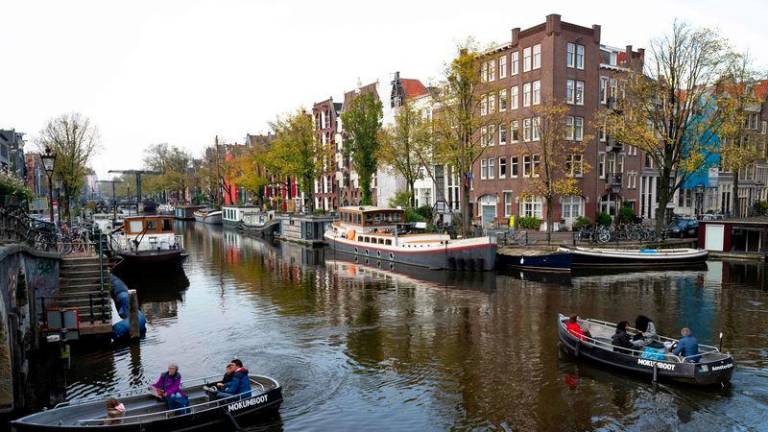 People navigate small boats on the Lekkersluis canal in Amsterdam on October 23, 2024, as the city launches its 750th anniversary celebrations. - AFPPIX