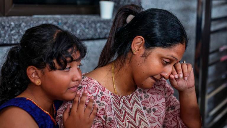 S. Sanggetha, 39, and her eldest daughter A. Hirsshika, 9, were overcome with emotion as they paid their last respects to the late S. Arumugam, 40, and their daughter A. Sarrvihka, 3, at their home near Taman Bayu Aman today. Photo by BERNAMA