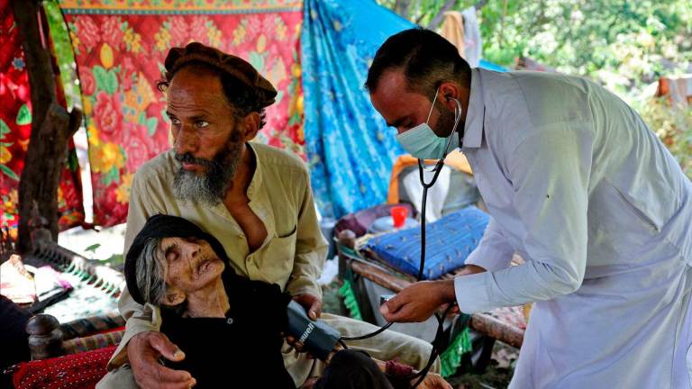Nazar Shah, 43, holds on to his mother, as Dr Hazrat Gul checks Rad Bibi, an injured Afghan woman who claims to be 110-years-old, outside her damaged house, following a deadly earthquake that struck Afghanistan’s Kunar and Nangarhar provinces, in Nurgal district, Kunar province, Afghanistan, September 4, 2025. REUTERS/Sayed Hassib TPX IMAGES OF THE DAY
