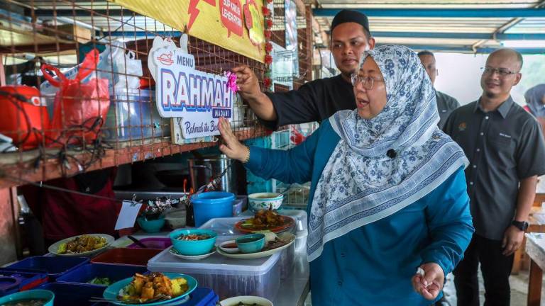 Timbalan Menteri Perdagangan Dalam Negeri dan Kos Sara Hidup Datuk Dr Fuziah Salleh melekatkan plakad menu RAHMAH disebuah kedai makanan yang menjual menu tersebut ketika program turun padang Jom Cari Menu RAHMAH yang diadakan Tanjung Gosong disini hari ini. - BERNAMA