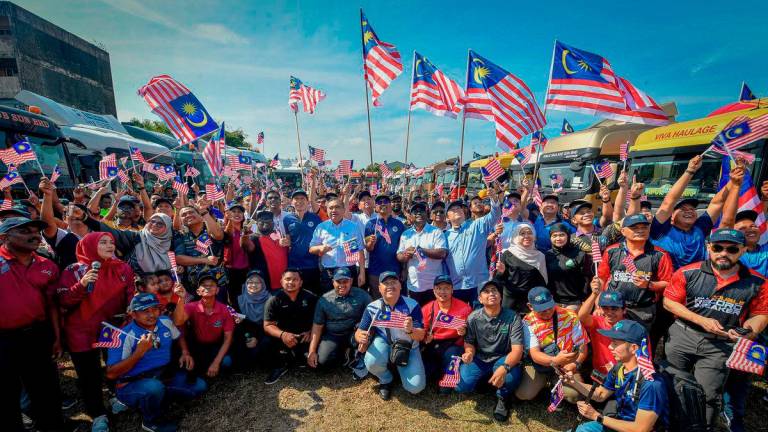 Menteri Pengangkutan Anthony Loke (tengah) bergambar selepas menyerahkan Jalur Gemilang kepada 100 wakil pemandu haulier pada Program Kibarkan Jalur Gemilang Komuniti Pelabuhan Klang di Bangunan Kelab Sosial dan Rekreasi Lembaga Pelabuhan Klang (LPK), Pelabuhan Klang hari ini. - BERNAMA