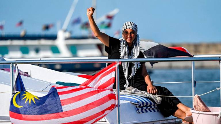 A woman gestures as she rides aboard a vessel with other activists and human rights defenders, departing from Tunisia’s northern port of Bizerte, on September 14, 2025. (Photo by MOHAMED FLISS / AFP)